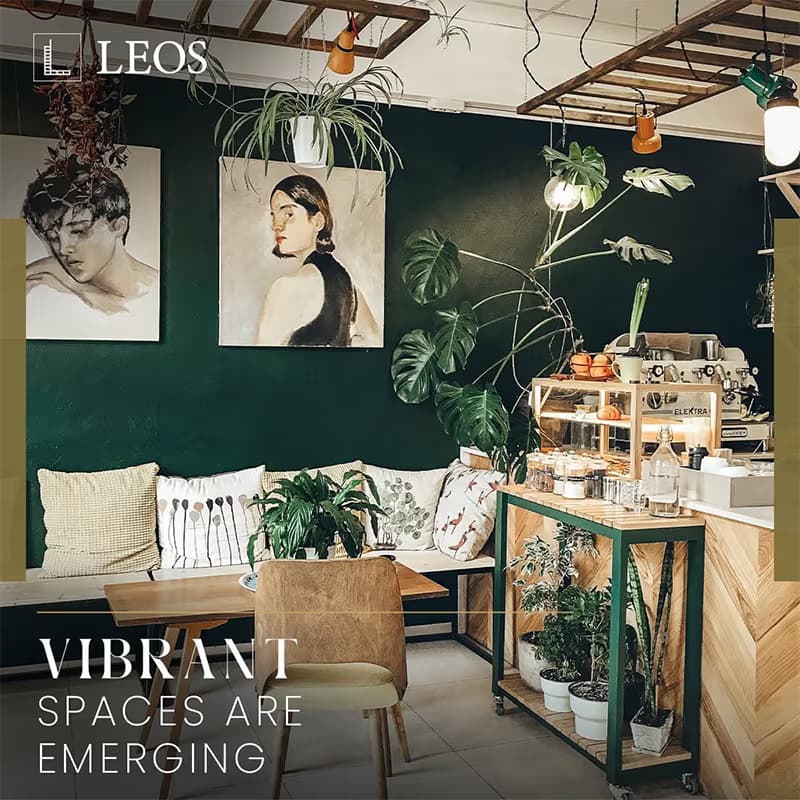 LEOS brand creative captioned Vibrant Spaces Are Emerging, showing a deep green interior with framed artwork, plants and lounge seating